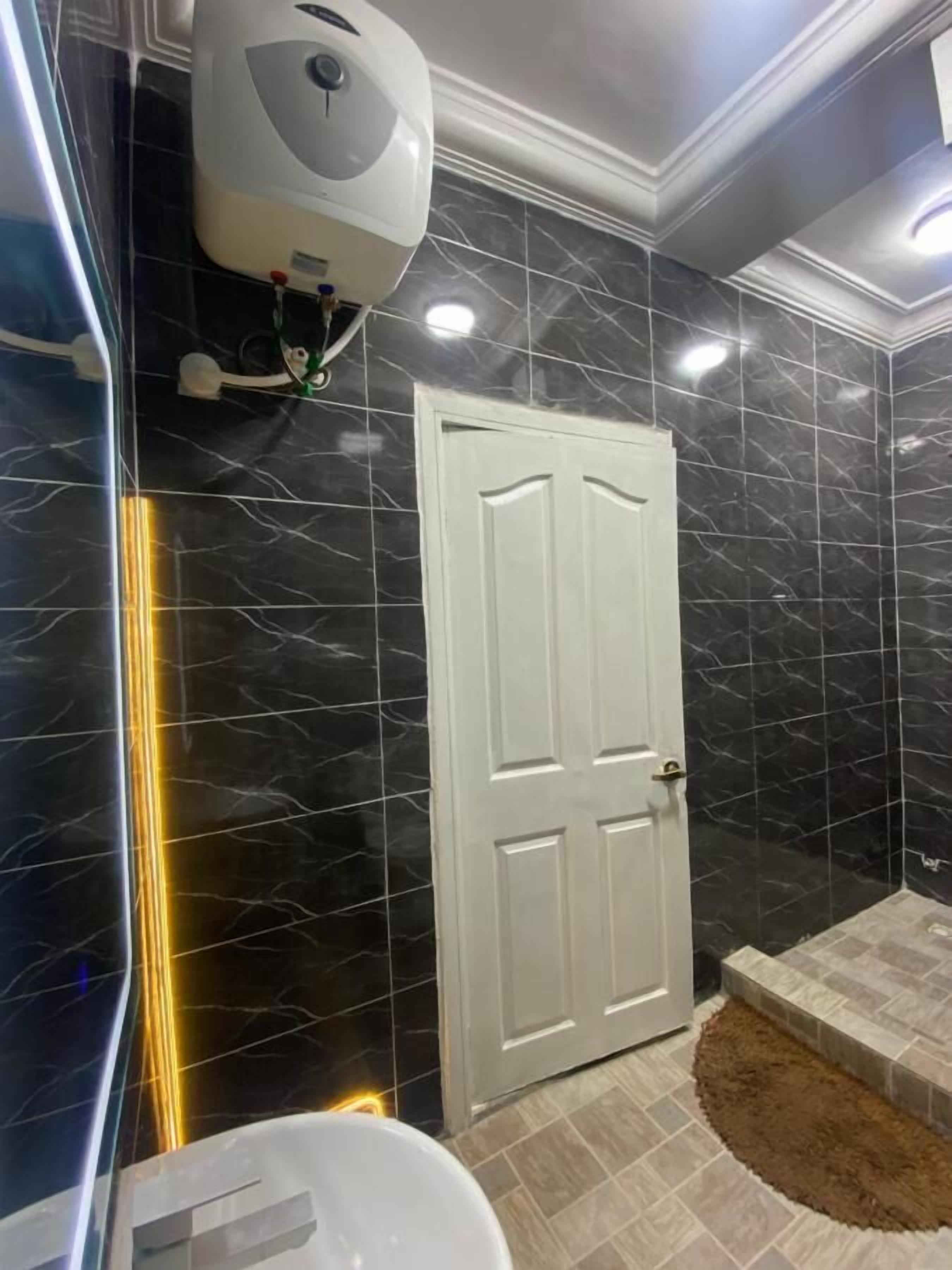 A bathroom with black marble walls, a white door, and a white toilet.