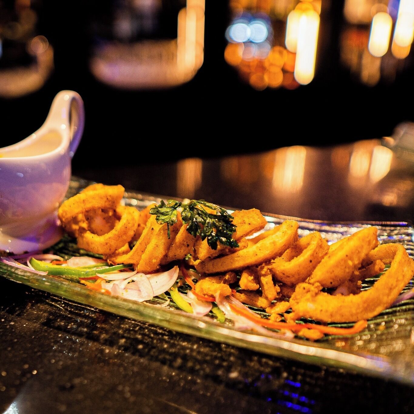 A plate of fried food with a small cup of sauce.