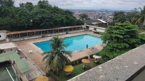 Une piscine entourée de verdure, avec une vue sur le paysage urbain en arrière-plan.