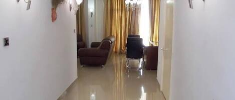 A hallway with a sofa, a chair, and a desk.