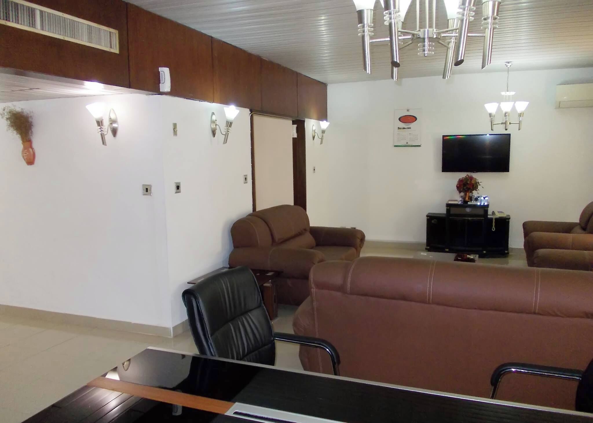 A modern living room with leather sofas, a flat-screen TV, and a dining area with a table and chairs.