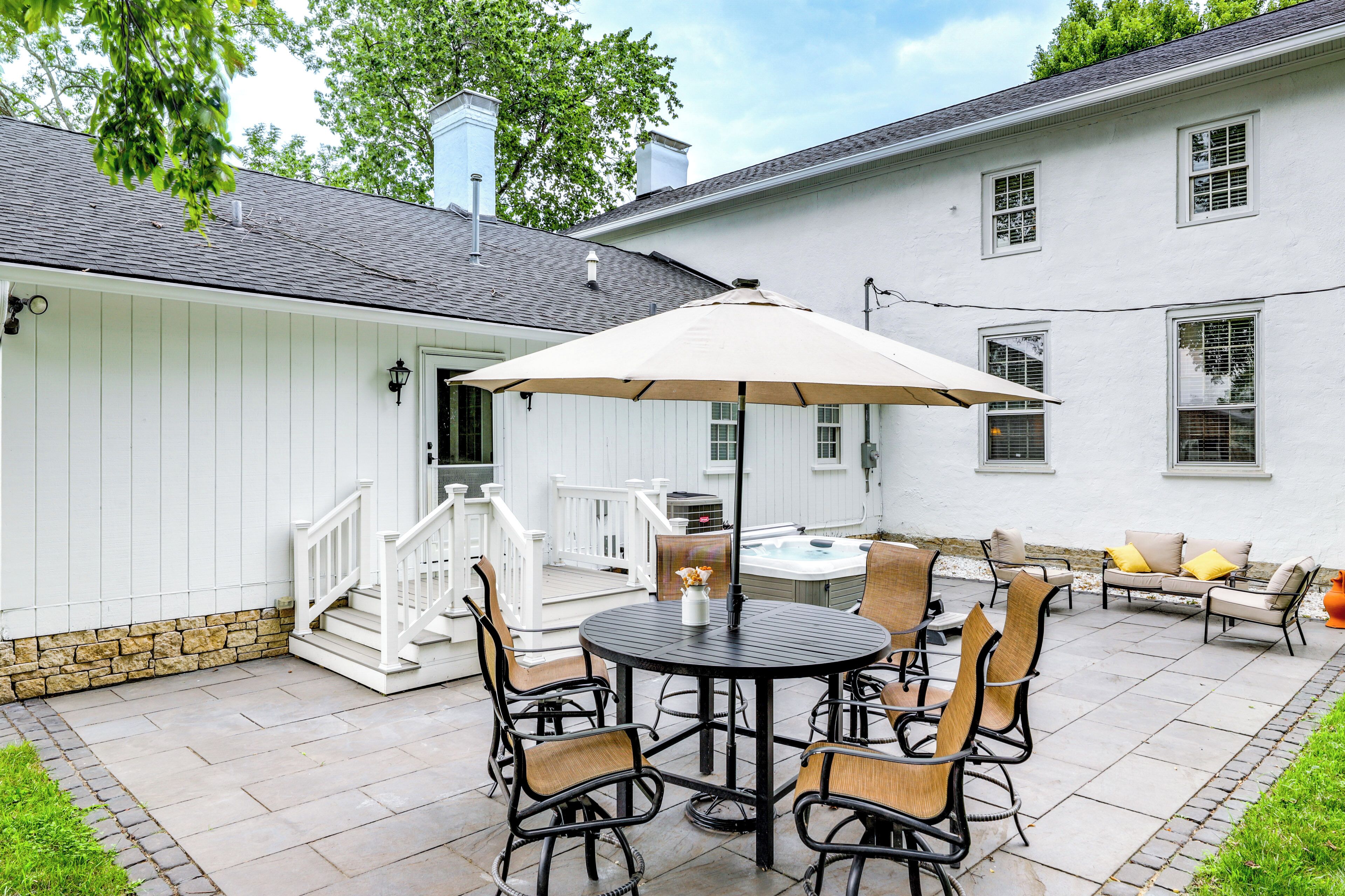 A patio with a round table, chairs, and a large umbrella.