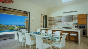 Una cucina moderna con isola centrale, mobili bianchi e vista sull'oceano.
