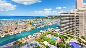 A marina with numerous boats docked, a hotel building with multiple balconies, and a clear blue sky. - Ocean and Sunset Marina Views at the Ilikai Hotel w/Great Building Amenities (Honolulu)