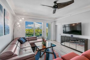 Uma sala de estar moderna com sofá, mesa de centro, TV e ventilador de teto.