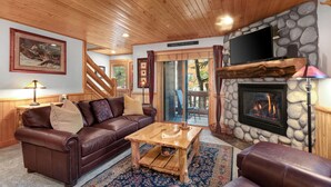 A cozy living room with a stone fireplace, leather furniture, and a television. - Managed by Park City Lodging-Great Condo Near Canyons Village-Free Shuttle Route (Park City)