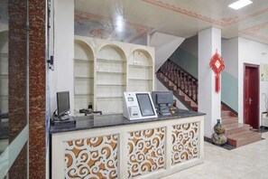 A reception area with a counter, a staircase, and a red decorative element. - Yangshuo Suiyuan Chengxi Inn (West Street Branch) (Yangshuo)