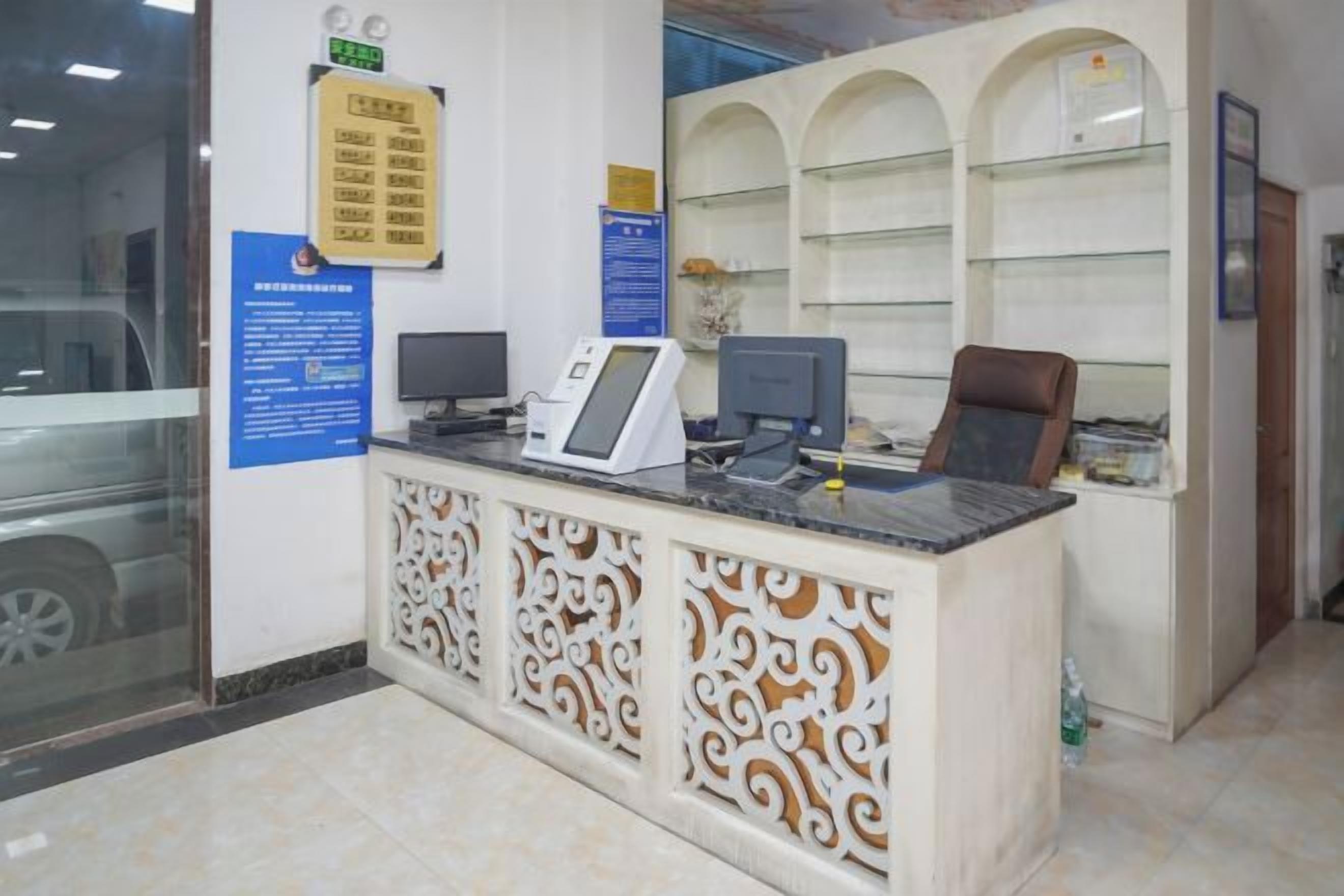 A reception desk with a computer, a chair, and a glass door.