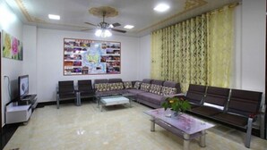 A waiting area with a sofa, chairs, a coffee table, a television, and a bulletin board. - Yangshuo Suiyuan Chengxi Inn (West Street Branch) (Yangshuo)