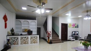 A spacious lobby with a reception desk, a staircase, a television, and a ceiling fan. - Yangshuo Suiyuan Chengxi Inn (West Street Branch) (Yangshuo)
