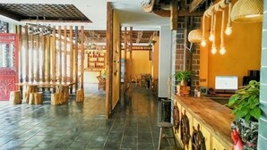 Een receptiegedeelte met een houten receptiebalie, een computer en een zithoek met stoelen en een tafel.