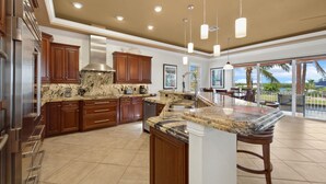 A spacious kitchen with granite countertops, wooden cabinets, and stainless steel appliances.