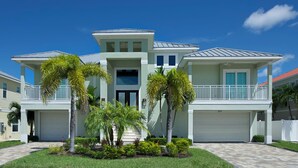 A two-story house with a garage, a balcony, and a well-maintained lawn. - ⭐Luxury Home with Private Pool and Outdoor Kitchen-Memories on Madison⭐ (Fort Myers Beach)