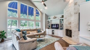 Un salón espacioso con un gran ventanal, chimenea y televisor.