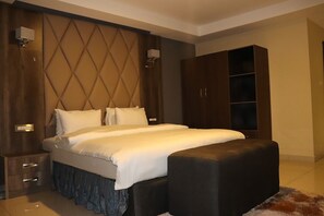 Une chambre à coucher moderne avec un grand lit, une table de chevet, une armoire et un banc.