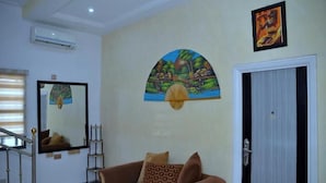 A living room with a sofa, a mirror, and a door. - Delad Hotel and Suites (Ibadan)