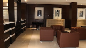 A modern living room with dark wood paneling, a beige sofa, and framed artwork on the walls. - Delad Hotel and Suites (Ibadan)