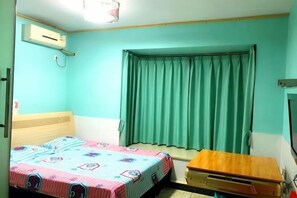 A room with a bed, a wooden desk, a window with curtains, and an air conditioning unit. - Jiangwen Apartment (Chongqing)
