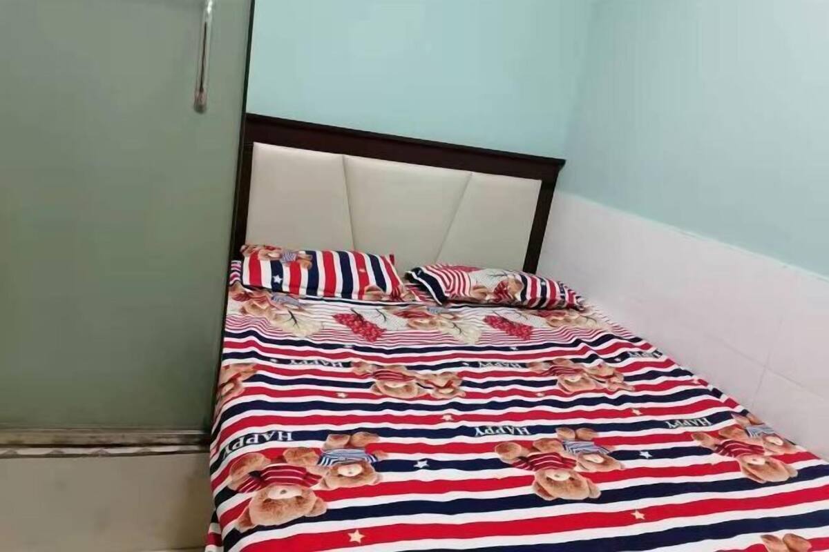 A bed with striped bedding and pillows, a wooden headboard, and a green wall.