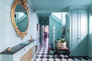 Stunning hallway with a checkered floor, ornate mirror, and elegant staircase.