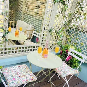Relax in this serene outdoor seating area, complete with a round table and two comfortable chairs, perfect for enjoying a glass of wine or juice amidst lush greenery.