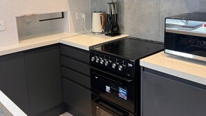 Een moderne keuken met zwarte kastjes, een inbouwoven en een magnetron.