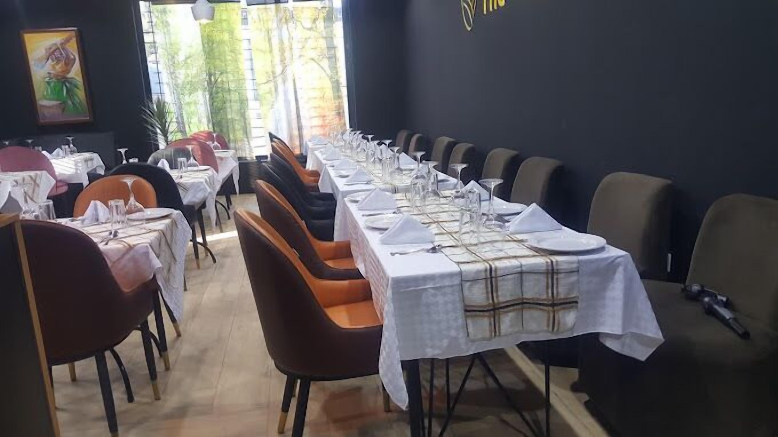 Un restaurante con mesas largas dispuestas para comer, sillas y un cuadro en la pared.