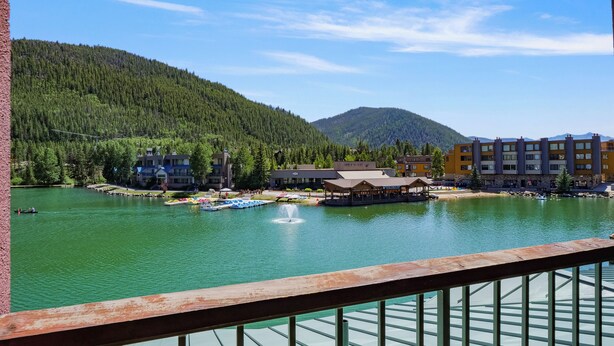 Vista de un lago con edificios, una fuente y una montaña al fondo.