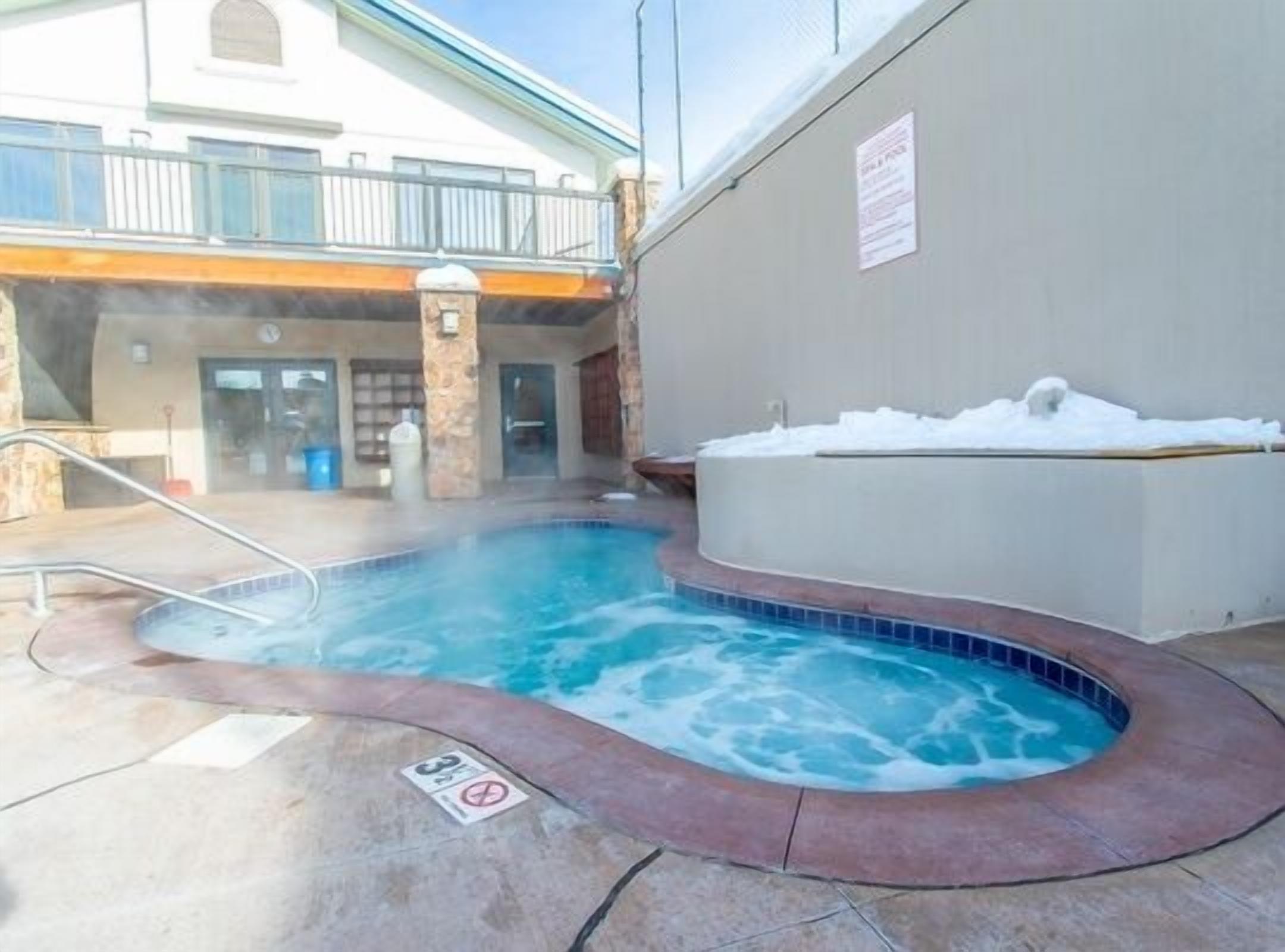 Zona de jacuzzi con piscina, un pilar de piedra y un letrero que indica una norma de tres minutos.