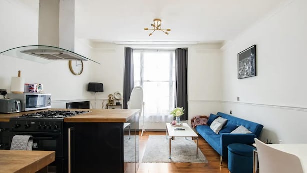 A modern living space with a kitchen, dining area, and a blue sofa. - Charming London Apartment Near Hyde Park (London)