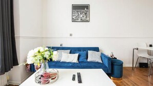 A living room with a blue sofa, a white coffee table, and a framed cityscape picture on the wall. - Charming London Apartment Near Hyde Park (London)