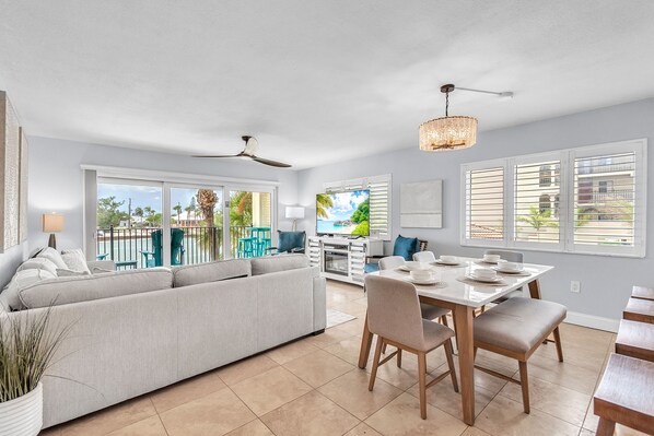 A modern kitchen with a dining area, large windows, and a view of the outdoors.
