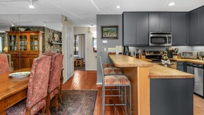 Una cocina moderna con armarios oscuros, una isla de madera y taburetes de bar.