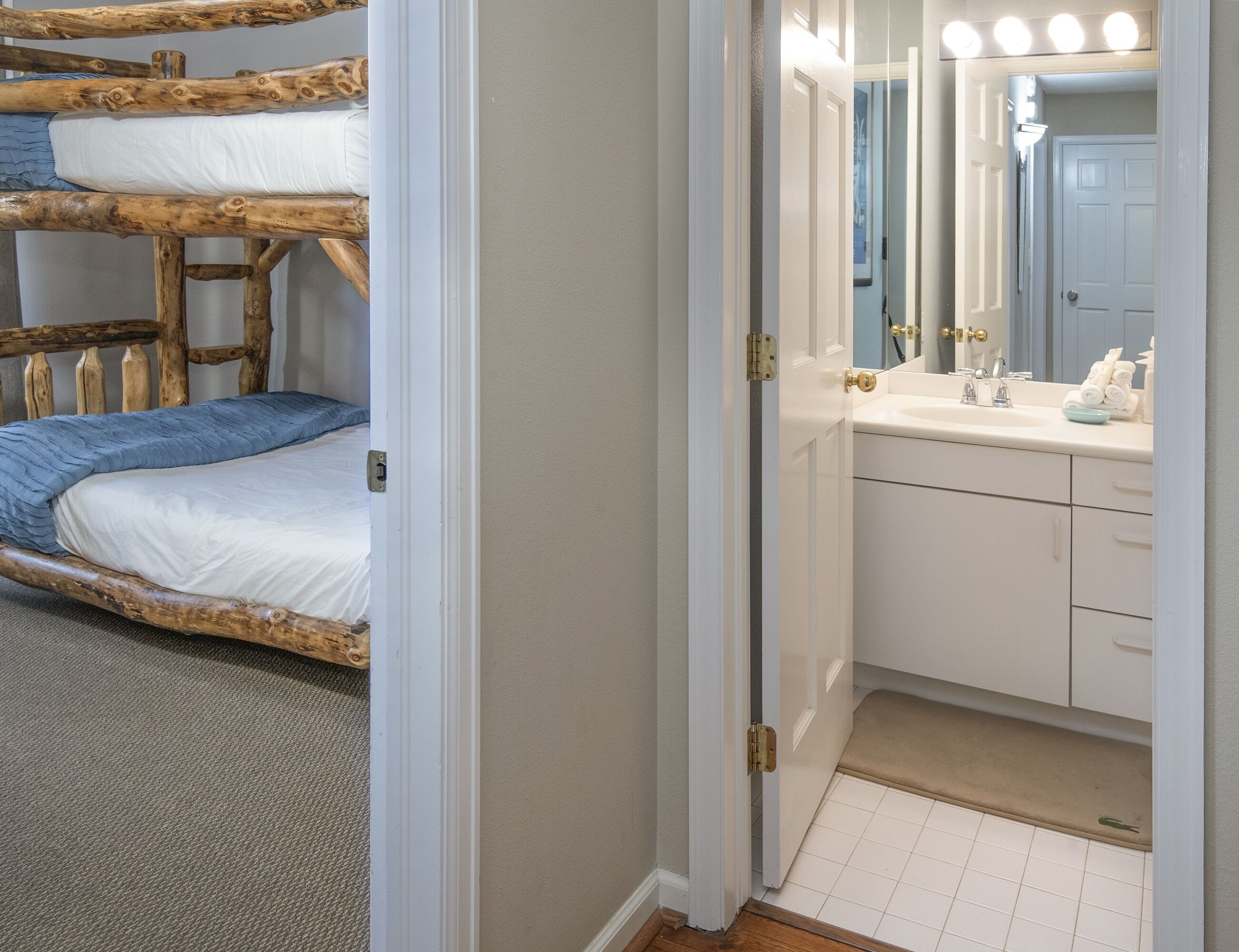 Una stanza con un letto a castello e un bagno con lavandino e specchio.