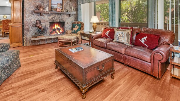 Una sala de estar acogedora con chimenea de piedra, sofá de cuero y una mesa de centro de madera.