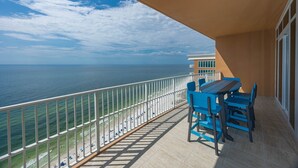 Un balcón con vista al mar, una mesa y sillas azules.
