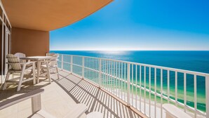 A balcony with a view of the ocean, white railings, and a table with chairs. - Phoenix Gulf Towers 2605 4 Bedroom Condo (Orange Beach)