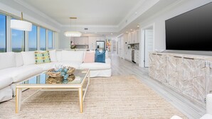 A spacious living room with a large sofa, a coffee table, and a television. - Phoenix Gulf Towers 2605 4 Bedroom Condo (Orange Beach)