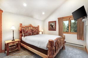 A bedroom with a rustic wooden bed frame, a bedside table with a lamp, a framed picture on the wall, and a window with curtains. - Timber Wolf Lodge 10d 2 Bedroom Condo by RedAwning (Park City)
