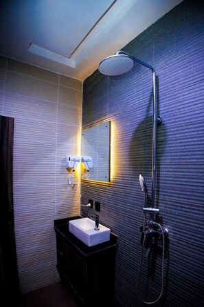 Une salle de bain moderne avec un lavabo rectangulaire, une douchette à main et un miroir fixé au mur.