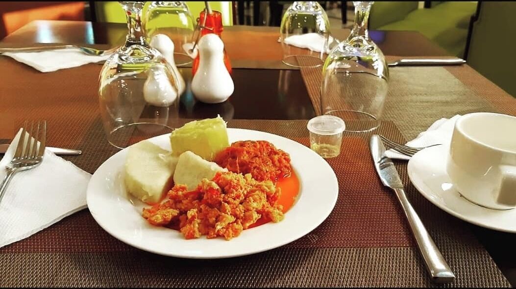 Una mesa de comedor con un plato de comida, copas de vino y cubiertos.