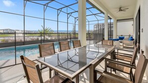 Une vaste terrasse extérieure dotée d’une table et de chaises en verre, d’une piscine et offrant une vue sur le paysage environnant.