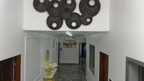 A hallway with a modern design, featuring a wall-mounted decorative panel and a marble floor. - Ashokas Hotel Ibadan (Ibadan)