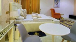 A modern hotel room with a bed, a dining table, and two chairs. - Ashokas Hotel Ibadan (Ibadan)