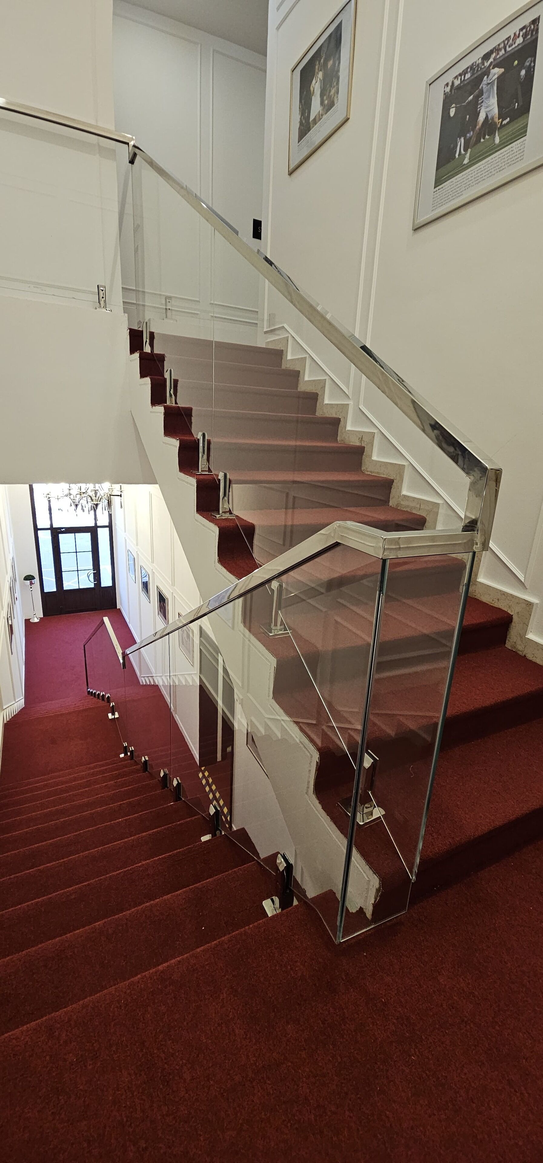A staircase with a glass railing and red carpet.