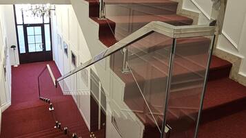 A staircase with a glass railing and red carpet.
