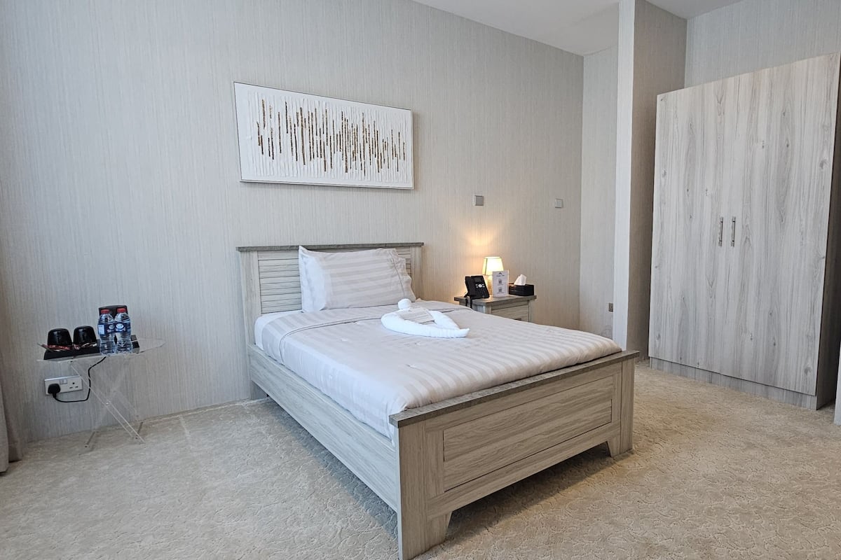 Ein modernes Schlafzimmer mit Bett, Nachttisch, Lampe und Kleiderschrank.