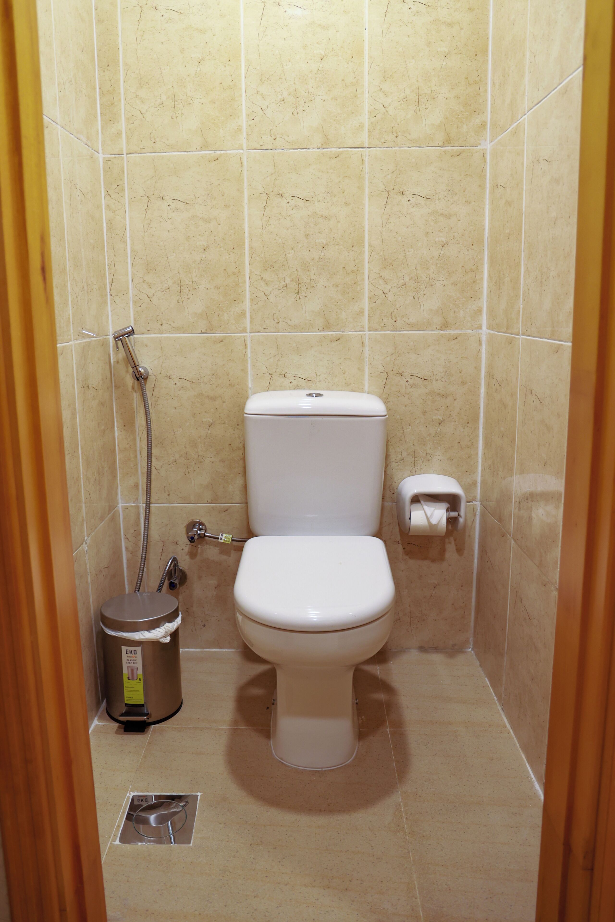 A small, clean bathroom with a toilet, a trash can, and a shower.
