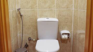 A small, clean bathroom with a toilet, a trash can, and a shower.