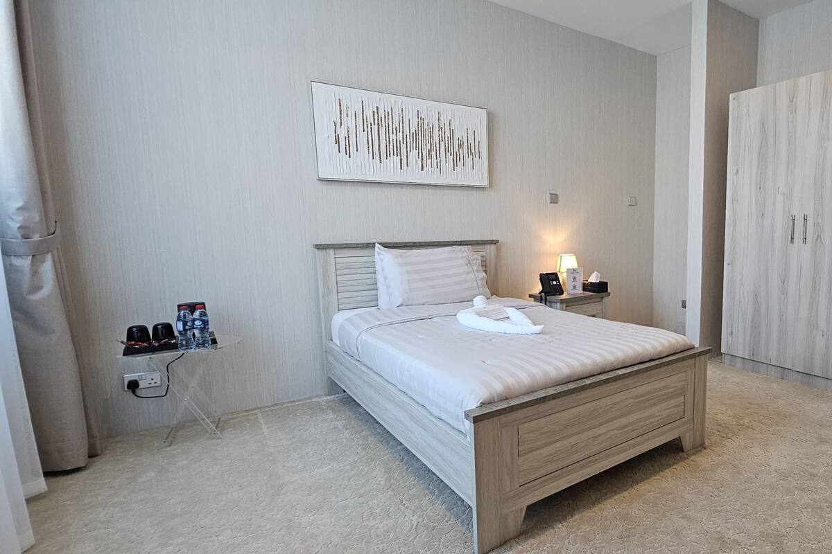 Ein modernes Schlafzimmer mit Bett, Nachttisch, Lampe und Kleiderschrank.